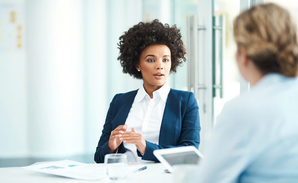 Two women at a desk having a conversation.