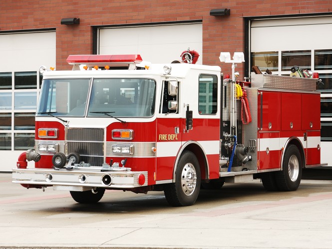 A fire truck parked outside a firehouse. 