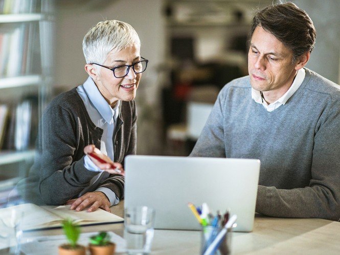 Two people sitting in front of a laptop. 