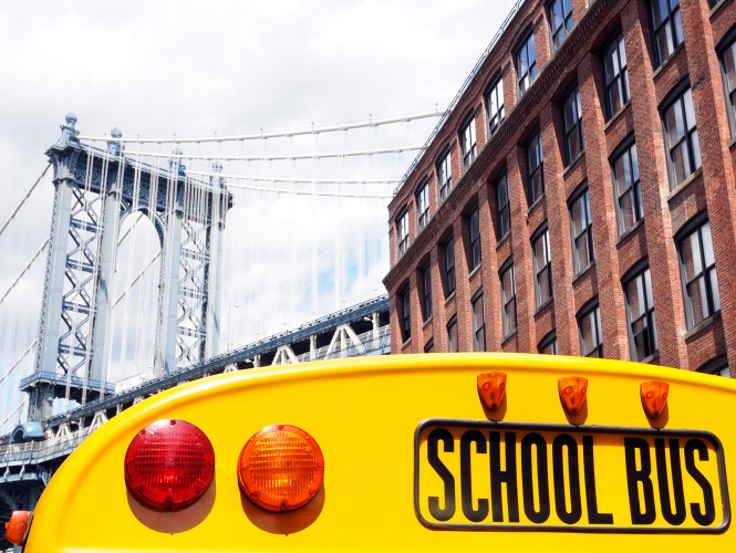 The back of a school bus with a bridge in the background.