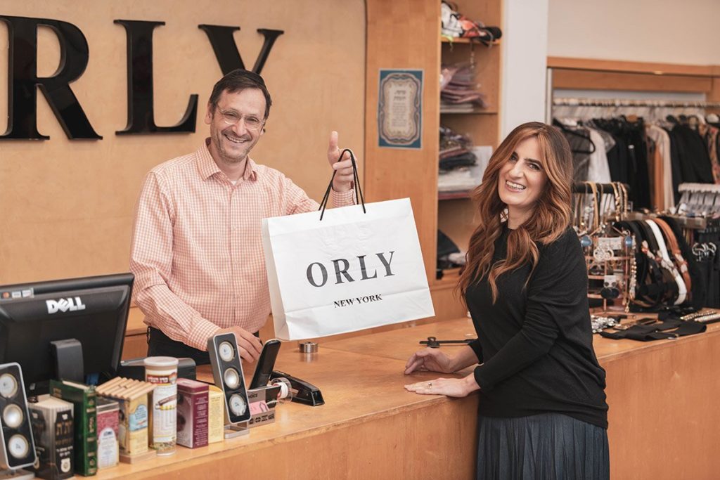 The co-founders of Orly in their business holding up a Orly bag. 