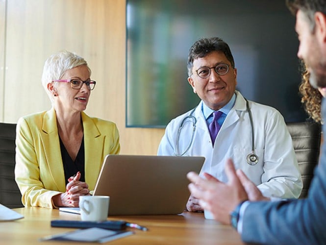 A doctor talking to 3 other people. 