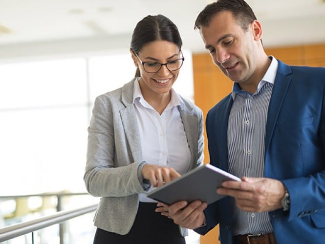 Two people looking at a tablet. 